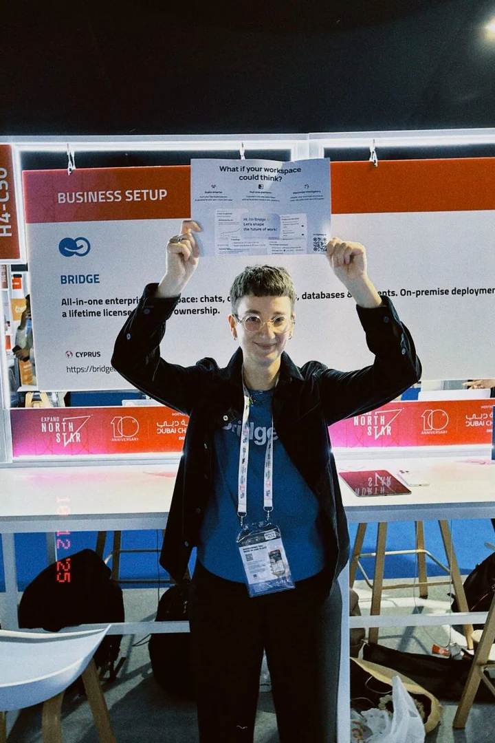 Maria Zhukova at the BridgeApp booth at Expand North Star in Dubai, holding up a flyer